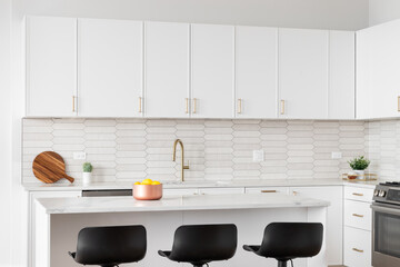 Wall Mural - A beautiful kitchen detail with white cabinets, a gold faucet, white marble countertops, and a brown picket ceramic tile backsplash. No brands or labels.