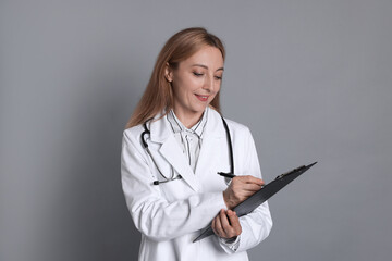 Wall Mural - Doctor with clipboard writing notes on gray background