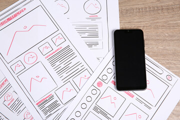 Leinwandbilder - Developing UI design. Sketches of website wireframes and smartphone on wooden table, top view