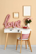 © Pixel-Shot - White desk with word LOVE made from balloons, bouquet of roses and books near beige wall. Valentine's Day celebration