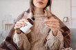 © Pixel-Shot - Sick young woman with plaid pouring cough syrup into spoon at home, closeup
