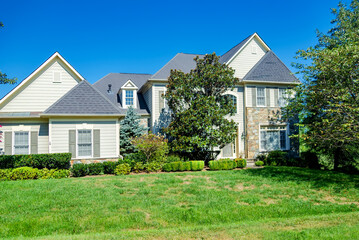 Landscape with large country house. Large mowed lawn and blue sky.