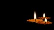 © Chalermrach - Close-up of intricate carved diya oil lamp with bright flame on dark background, light, glowing