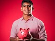 © mongkonchai - Youth saving money with piggy bank studio setting portrait bright background financial literacy concept