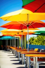 Wall Mural - Outdoor seating area with a row of colorful umbrellas providing shade for tables and chairs. The vivid umbrellas create a cheerful ambiance perfect for dining, relaxing, or socializing during the day.