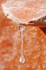 Wall Mural - Close-Up of Dripping Water from Stone Spout in Sunlit Spring Scene