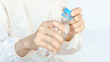 © Oporty786 - A person holds a plastic water bottle, preparing to open it, showcasing hands and a blue cap against a light background.