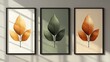 © Gaming - Triptych of stylized leaf prints in gold, green, and copper tones, framed and displayed on a wall.