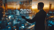 © Atchariya63 - Businessman analyzing data projections for 2025 in a futuristic urban setting.