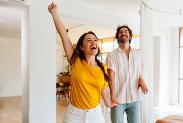 Happy young couple relocating in a new apartment. Young woman and man working and arranging the new property they just bought. Moving stuff and boxes together.