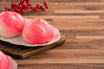 Wall Mural - Pink Chinese peach birthday bun food shoutao on wooden table background.