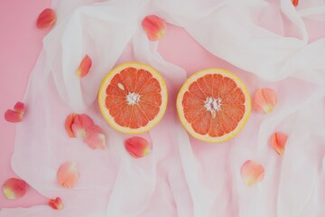 Wall Mural - Citrus Delight: Flat Lay of Ripe Grapefruit Halves with Petals on Pink Fabric