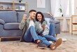 © Studio Romantic - Happy excited young couple with smartphone, husband and wife relax on floor in living room feel euphoric, win lottery online cellphone, overjoyed with good unexpected news on smartphone gadget at home