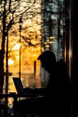 Poster - A man is sitting at a table with a laptop, looking at the screen