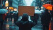 © musa - Person holding blank sign at rainy protest.