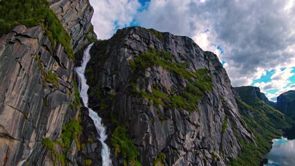 Aufkleber - Majestic waterfall cascading down rocky cliffs in a serene landscape during midday