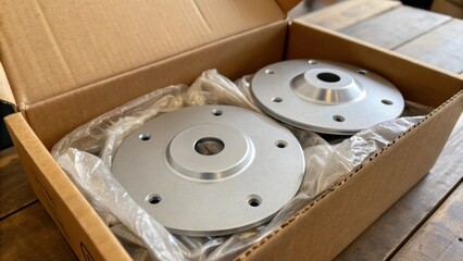 Poster - A close view of an open box of ceiling fan mounting brackets with several pieces gleaming in the light ast the cled packing material. The contrasting textures of the smooth metal
