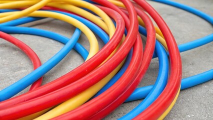 Aufkleber - An artistic closeup featuring a tangle of colorful PEX tubing showcasing an array of bright reds blues and yellows. The flexible pipes twist and crossover in a dynamic fashion