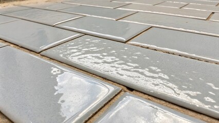 Poster - Zooming in on a section of light gray grout being spread over the tile joints revealing the subtle variations in color and texture. The shiny liquid is oozing into the spaces