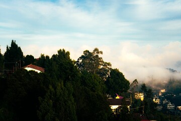 Poster - Hillside town with misty clouds and blue sky.