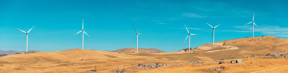 wind turbines standing on a dry hilly landscape, generating renewable energy under a clear blue sky