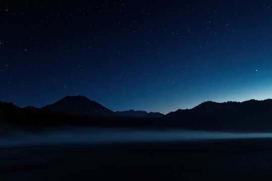 A mountain range is silhouetted against a dark sky