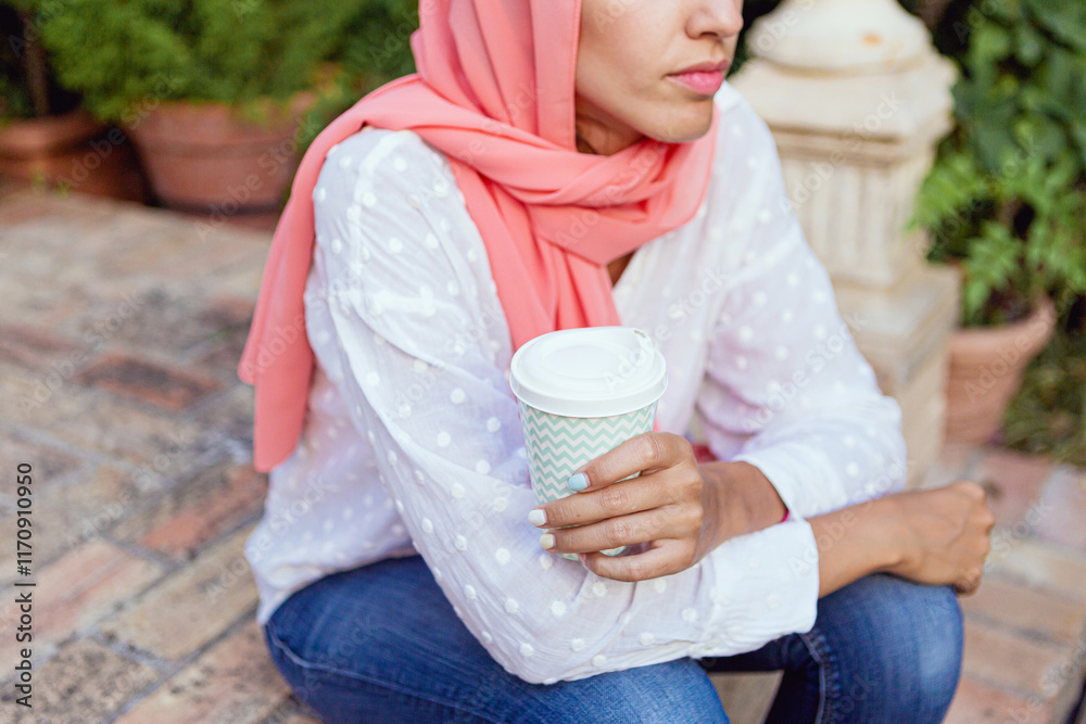 Portrait of a young and beautiful Muslim woman smiling and drinking ...