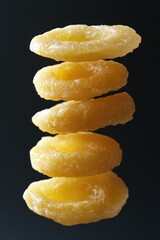 Poster - Stack of five dried apricots floating against a black background.