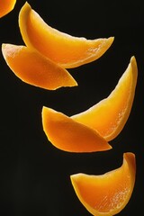 Poster - Several vibrant orange fruit slices levitate against a stark black backdrop, showcasing their juicy texture and bright color.