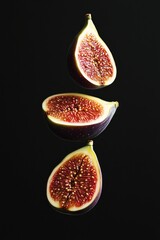 Poster - Three halved figs levitate against a black background, showcasing their vibrant red interior and intricate seed patterns.