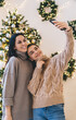 © BullRun - Smiling women taking selfie against Christmas decoration at home