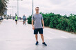 © BullRun - Portrait of cheerful muscular male runner standing on street enjoying workout and music in earphones, cheerful sportsman satisfied with online radio songs keeping healthy lifestyle and fit outdoors