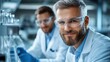 © Denis - Scientists conducting laboratory experiments with glassware and equipment in a modern research facility during daylight hours