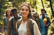 © Worrapol - Young woman with backpack smiling on forest trail with friends during outdoor adventure in sunny weather, exploring nature and enjoying hiking experience