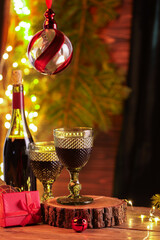 Canvas Print - Red wine and beautiful Christmas decor on wooden table against blurred festive lights. Space for text