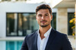 © Vitalii - A beautiful male real estate agent with a luxury villa in the background