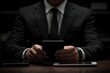 © Robi - Businessman in black suit using mobile phone during working at office with digital tablet and