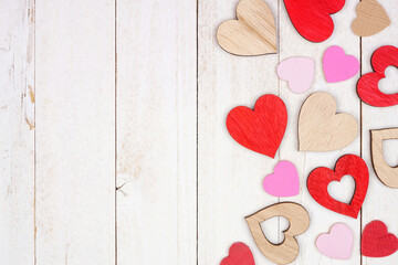 Poster - Valentines Day side border of wooden hearts. Overhead view on a white wood background. Copy space.
