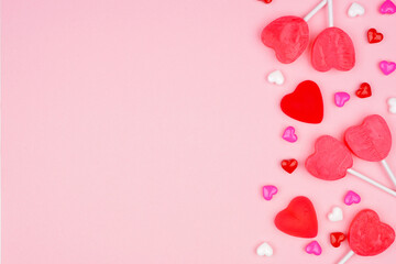 Poster - Valentines Day side border of candy hearts and lollipops. Overhead view on a pink background. Copy space.