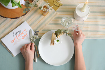 Poster - Female hands with beautiful table setting and greeting card for International Women's Day celebration, closeup