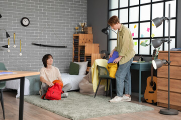 Wall Mural - Male students packing backpacks in bedroom