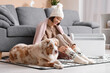 © Pixel-Shot - Young woman in winter clothes with blanket and Australian Shepherd dog sitting on floor near heater at home