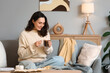 © Pixel-Shot - Beautiful young happy woman with cup of hot chocolate and marshmallows sitting on sofa at home