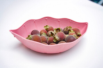 Photo of kemunting or karamunting fruits in a pink leaf-shaped plate