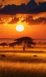 Golden Hour on the African Savannah, A fiery sunset casts long shadows across the grasslands as silhouetted acacia trees and grazing animals create a scene of tranquil beauty,