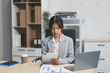 © Kansuda - Successful Asian businesswoman smiling using laptop computer and holding coffee cup at office. Confident Asia businesswoman sitting happily in the office.
