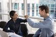 © fizkes - Cheerful office coworkers making fist bump friends gesture, discussing project success, teamwork, collaboration strategy, successful startup, creative ideas. Happy diverse colleagues getting agreement