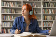 © fizkes - Pensive young woman student learn foreign language at online interactive video course sit by notebook screen in headset look aside think on text translation ponder on exercise before write to copybook