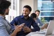 © fizkes - Positive handsome African American project manger man meeting with male Indian colleague at large co-working table, talking to coworker, smiling, laughing, enjoying business communication, networking