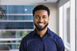 © fizkes - Cheerful handsome young African American businessman posing for head shot in office, looking at camera with toothy smile. Confident successful Black business leader man, startup manager portrait